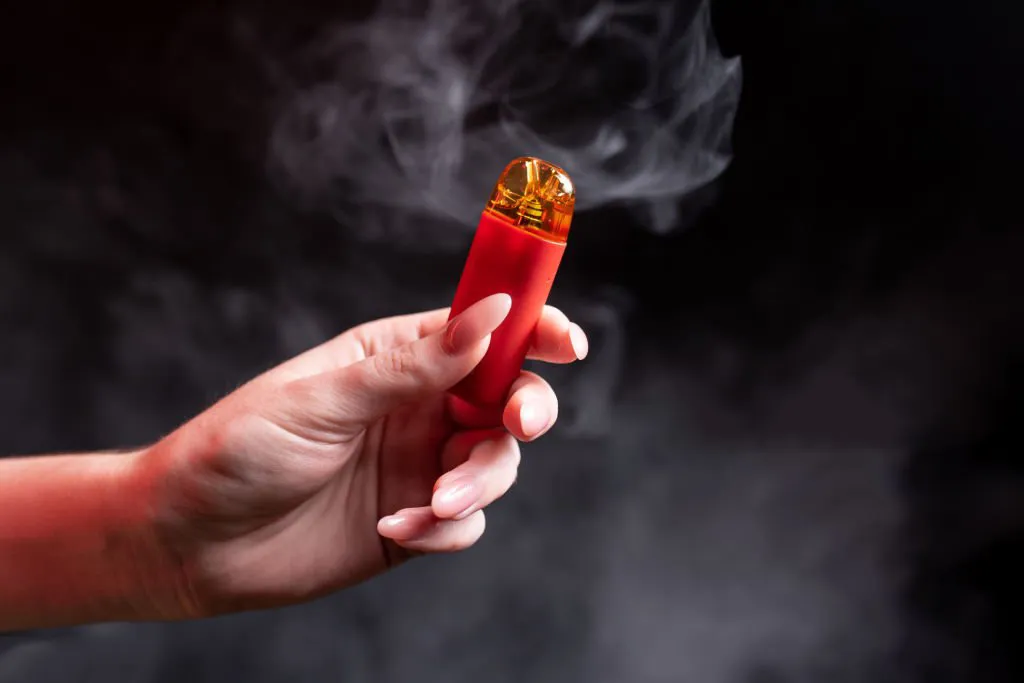 在黑色背景中一只手拿著一個電子煙煙彈